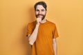 Caucasian man with beard wearing casual yellow t shirt looking confident at the camera smiling with crossed arms and hand raised Royalty Free Stock Photo