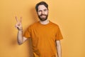 Caucasian man with beard wearing casual yellow t shirt smiling with happy face winking at the camera doing victory sign with Royalty Free Stock Photo