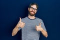 Caucasian man with beard wearing striped t shirt and glasses success sign doing positive gesture with hand, thumbs up smiling and Royalty Free Stock Photo