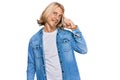 Caucasian man with blond long hair wearing casual denim jacket smiling pointing to head with one finger, great idea or thought,