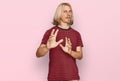 Caucasian man with blond long hair wearing casual striped t shirt disgusted expression, displeased and fearful doing disgust face