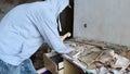 Caucasian man in cap and hood phone with broken phone in abandoned building. Hacker, racketeer, terrorist concept