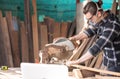 Caucasian man carpenter cutting wood with circular saw creating new furniture