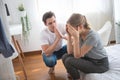 caucasian man comforting sad and unhappy beautiful girl sit on bedd in bedroom at home