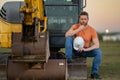 Caucasian man, construction worker in helmet at construction site. Industry engineer worker in hardhat near bulldozer or