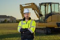 Caucasian man, construction worker in helmet at construction site. Industry engineer worker in hardhat near bulldozer or