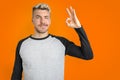 Caucasian man doing OK gesture with hands and winking. Isolated orange background Royalty Free Stock Photo