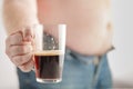 Caucasian man with Fat Beer Belly, holding a glass of dark ale.