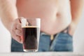 Caucasian man with Fat Beer Belly, holding a glass of dark ale.