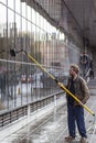 A caucasian man with ginger hair is cleaning the windows of a galss building