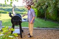 Caucasian man grilling food outdoors over a charcoal barbecue. Royalty Free Stock Photo