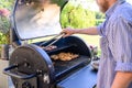 Caucasian man grilling food outdoors over a charcoal barbecue. Royalty Free Stock Photo