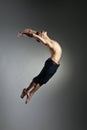 Caucasian man gymnastic leap posture on grey