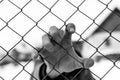 Caucasian man hand holding the wire fence at correctional institute