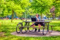 Caucasian man with headphones sitting on the bench at the park and looking at his laptop in Montreal, Canada