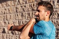 Caucasian man in his 30s stretching and warming up the muscles of the arm, forearm, triceps and shoulder, before and after outdoor