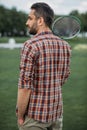 Caucasian man holding badminton racquet and standing on green field Royalty Free Stock Photo