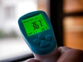 Caucasian man holding a digital non contact infrared thermometer showing normal human temperature Royalty Free Stock Photo