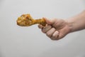 Caucasian man holds a crispy cooked a chicken leg