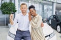 Caucasian man holds keys from his new car in dealership Royalty Free Stock Photo