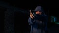 Caucasian man in a hood shoots a pistol.