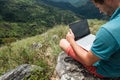 Caucasian man with laptop sitting on the edge of ella mountain with stunning views of the valley in Sri Lanka.