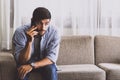 Caucasian man with mustache and beard talking with mobile phone in living room about serious problem