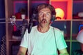 Caucasian man with mustache playing video games wearing headphones scared and amazed with open mouth for surprise, disbelief face Royalty Free Stock Photo