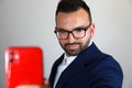 Caucasian man in a navy blue suit and glasses taking a selfi Royalty Free Stock Photo