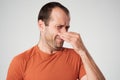 Caucasian man is pinching nose with fingers and looking with disgust because of bad smell isolated on white background Royalty Free Stock Photo