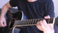 Caucasian man playing chords in a black acoustic guitar