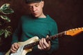 Caucasian man playing electric guitar against dark wall. Home leisure concept. Portrait of handsome guitarist. Royalty Free Stock Photo