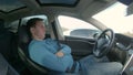 Caucasian man reclines in the driver`s seat of a self steering car during a motorway traffic jam.