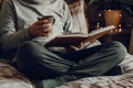 A caucasian man relaxing at home, reading a book, drinking coffee in bed Royalty Free Stock Photo