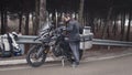 A Caucasian man removes the kickstand from his motorbike
