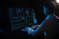 A caucasian man sits in the dark in front of a virtual menu and types on a keyboard. Readings on the life support