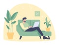 Caucasian man sitting on green sofa working on laptop at home. Casual remote work, cozy indoor setting with plants Royalty Free Stock Photo