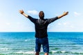 Caucasian man spreading arms,watching ocean. happy man with outstretched arms.rear view beach summer blue sky clouds Royalty Free Stock Photo