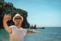 Caucasian man taking a selfie with smartphone in Split Apple Rock, Abel Tasman National Park, New Zealand Royalty Free Stock Photo