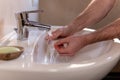 Caucasian man thoroughly cleaning hands and fingernails with a brush in wash basin under running water tap. Personal hygiene Royalty Free Stock Photo