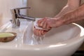 Caucasian man thoroughly cleaning hands and fingernails with a brush in wash basin under running water tap. Personal hygiene Royalty Free Stock Photo