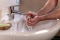 Caucasian man thoroughly cleaning hands and fingernails with a brush in wash basin under running water tap. Personal hygiene Royalty Free Stock Photo