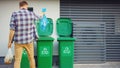 Caucasian Man is Throwing Away Two Plastic Bags of Trash next to His House. One Garbage Bag is Royalty Free Stock Photo