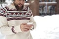 Caucasian man using mobile phone in front of wooden house in winter Royalty Free Stock Photo