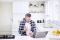 Caucasian man using phone and laptop in kitchen Royalty Free Stock Photo