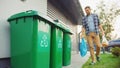 Caucasian Man is Walking Outside His House in Order to Take Out Two Plastic Bags of Trash. One Royalty Free Stock Photo