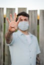 Caucasian man wearing face mask counting four with hand. Coronavirus Covid-19 concept