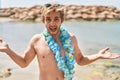 Caucasian man wearing hawaiian lei at the beach celebrating achievement with happy smile and winner expression with raised hand Royalty Free Stock Photo