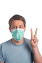 Caucasian man wearing a protection mask making victory sign on a white background