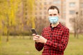 Caucasian man wearing shirt and protective mask against virus standing outdoor using smart phone mobile to send messages Royalty Free Stock Photo